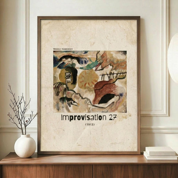 May include: Framed poster print of Wassily Kandinsky's abstract expressionist painting featuring flowing organic shapes in earth tones of ochre, burgundy, green and black against cream background. The vintage-style print shows "Improvisation 27 (1912)" text below the artwork. Wooden frame sits on mid-century walnut credenza beside white ceramic vase with bare branches and stack of books against cream walls with white crown molding.