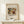 May include: Framed art print featuring Wassily Kandinsky's abstract expressionist painting with swirling forms in earth tones, blues, and reds, displayed in light wood frame on white wooden surface against cream wall. Small wrapped gift with twine and evergreen sprig sits beside frame.