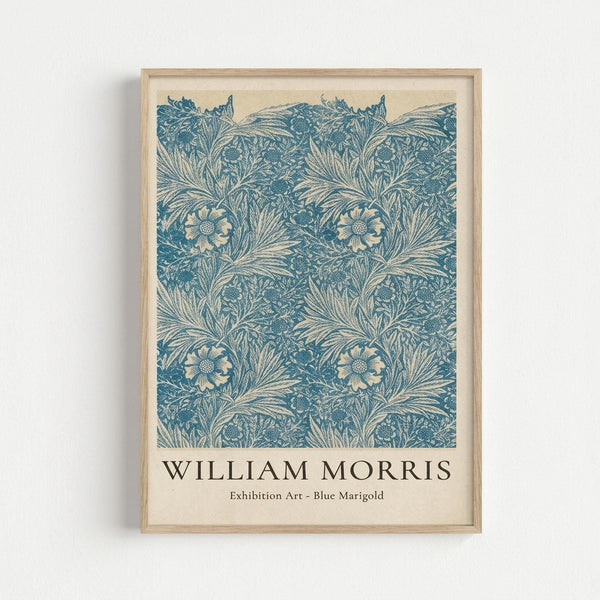 May include: Framed art print featuring an intricate blue floral pattern with marigold flowers and flowing botanical motifs on cream background, displayed in light wood frame against white wall. The design shows repeating ornate flowers with detailed petals and swirling leafy stems in vintage decorative style.