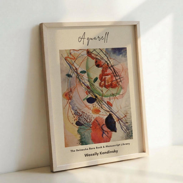 May include: Abstract watercolor artwork in light wood frame leaning against white wall. Painting features swirling organic shapes in red, green, blue, and orange with flowing black lines and geometric elements. Frame has cream matting with artist name and library text below artwork. Soft natural lighting creates gentle shadows on textured white surface.