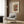May include: Framed abstract art print hanging on wood paneled wall above modern cream armchair with geometric pillow. Colorful watercolor artwork features swirling lines, circles and organic shapes in red, orange, green and blue tones. Contemporary room setting with brass floor lamp, dark side table with open book, and natural lighting from window with curtains.