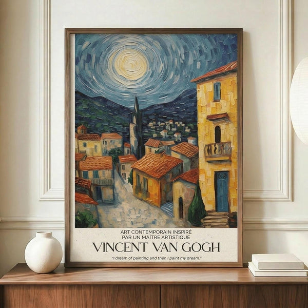 May include: Framed art print showing a Mediterranean village scene with yellow stone buildings, terra cotta roofs, and a church spire under a swirling blue night sky with bright moon. The painting uses thick brushstrokes in Van Gogh's distinctive style. Text below reads "Vincent Van Gogh" with French caption. The brown-framed poster sits on a wooden console table beside a white ceramic vase and books against cream paneled walls.
