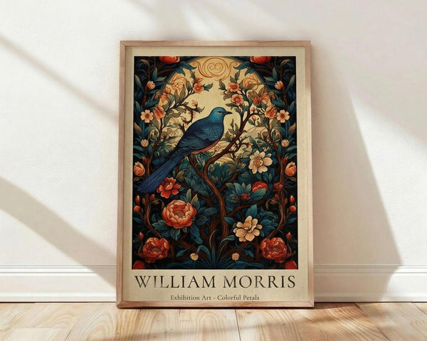 May include: Framed poster print in light wood frame leaning against white wall on wooden floor. Features ornate botanical design with blue bird perched among flowering vines, orange and coral blooms, and decorative scrollwork in William Morris style. Rich teal, coral, and cream colors with vintage aesthetic. Text below reads "WILLIAM MORRIS Exhibition Art - Colorful Petals." Natural lighting creates soft shadows on textured white wall.