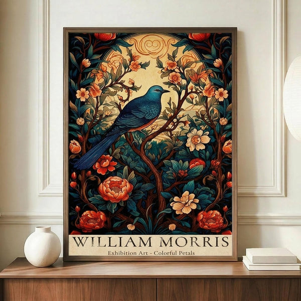 May include: Framed William Morris-style art print featuring a blue bird perched among ornate flowering vines with red peonies and cream blossoms against a dark teal background. The botanical illustration shows intricate Art Nouveau patterns with decorative border elements. Display shows poster in brown frame on wooden console table beside white ceramic vase and stack of books in elegant room with cream wainscoting and molding.