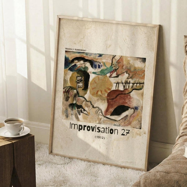 May include: Framed art print leaning against white wall corner on textured cream rug. Abstract expressionist artwork features bold brushstrokes in earth tones - ochre, green, burgundy, black and white forms suggesting figures and landscapes. Wooden frame with light matting. Coffee cup on wooden block nearby, cream fabric visible at edge. Natural window light creates soft shadows on wall.