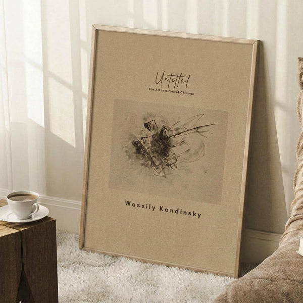 May include: A framed abstract art print with beige background featuring flowing black lines and organic shapes, displayed on a white textured rug in a bright room corner with natural light from windows creating geometric shadows on white walls, alongside a white coffee cup on saucer placed on a dark wooden block and neutral fabric.