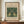 May include: Framed vintage botanical poster featuring William Morris Fragment 1876 design with symmetrical green parrots among pink flowers and foliage on cream background, displayed on wooden sideboard beside white ceramic vase and stacked books in elegant room with white paneled walls