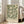 May include: Framed botanical art print with sage green background and cream-colored flowing acanthus leaves and flowers in vintage Arts and Crafts style, leaning against white wall near beige upholstered sofa in bright living room with large windows and natural lighting on hardwood floors.