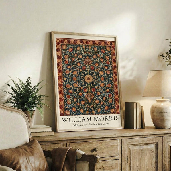 May include: Framed poster featuring an ornate carpet design with intricate floral patterns in teal, burgundy, and gold tones, displayed on a rustic wooden sideboard alongside books, a ceramic vase, and a fern plant in a cozy living room setting with neutral walls and upholstered furniture.