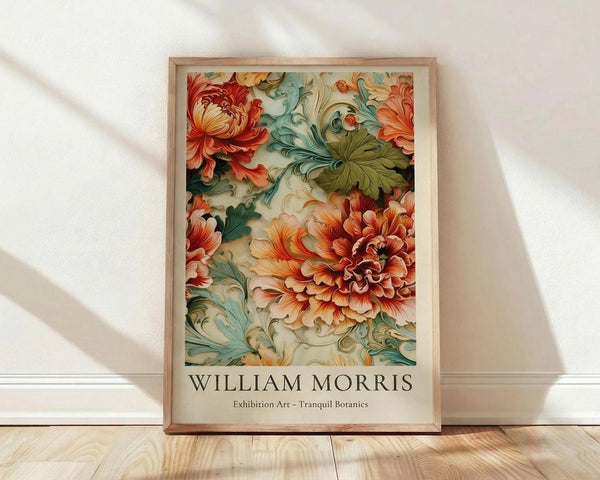 May include: Framed botanical art print leaning against white wall on light wood floor. Artwork features ornate orange and coral peonies with flowing teal and green foliage in decorative Victorian style. Natural wood frame with light finish. Soft natural lighting creates diagonal shadows across white textured wall. Print displays "WILLIAM MORRIS" and "Exhibition Art - Tranquil Botanics" text below floral design.