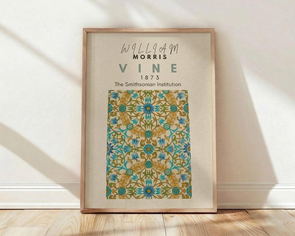 May include: Framed botanical poster with ornate floral pattern in turquoise, golden yellow, and green tones, displayed against white wall on light wood floor. Natural wood frame contains vintage-style decorative design with intricate vine motifs and symmetrical flower arrangements on cream background.