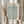 May include: Person in beige ruffled sleeves holding framed botanical print with sage green willow leaf pattern on cream background, natural light streaming through curtains, dried pampas grass stems visible, soft neutral home decor setting with wooden frame.