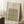 May include: Framed art print featuring William Morris floral vine pattern in blue, teal, and golden yellow colors from 1873, displayed leaning against white wall corner near wooden side table with coffee cup and cozy throw blanket in bright natural lighting