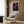 a cozy living room with a white armchair, a floor lamp, and a framed poster of Vavoi Usama, a famous Japanese street artist, hanging on the wall.
