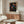a modern living room with a large abstract art poster on the wall, a wooden cabinet, a white sofa, and a glass coffee table.