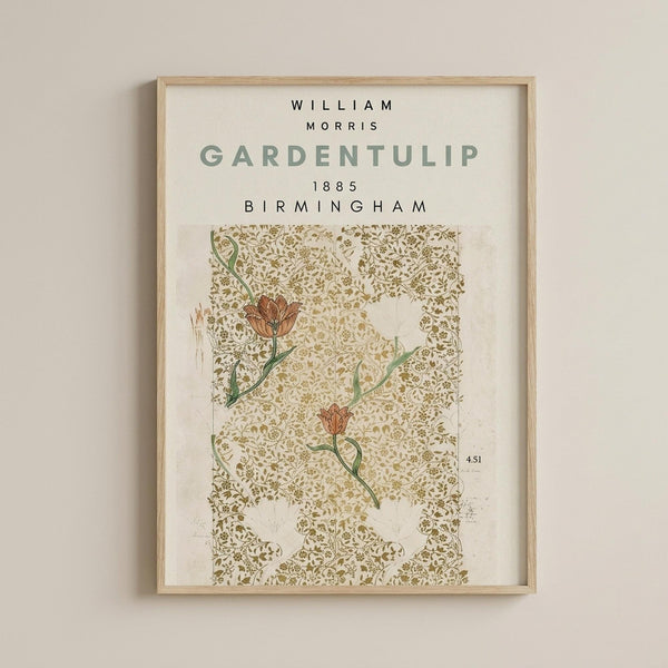 May include: Framed poster print hanging on beige wall featuring William Morris Garden Tulip pattern from 1885 Birmingham. Design shows red-orange tulips with green stems against intricate golden-brown decorative background with swirling botanical motifs. Light wood frame with white matting surrounds the vintage Arts and Crafts wallpaper design.