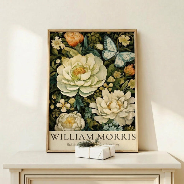 May include: Framed botanical art print featuring cream and white peonies, orange ranunculus, blue butterfly, and small flowers on dark green background, displayed on light wood console table next to small white wrapped gift with twine and sprig accent against cream wall