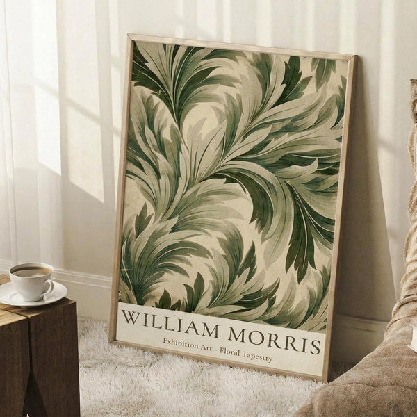 May include: Framed poster with flowing green and cream botanical leaf design in ornate swirling pattern, displayed in light wood frame leaning against white wall. Cozy room setting with white coffee cup on wooden surface, cream textured rug, and soft beige throw blanket with natural window lighting creating gentle shadows.