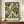 May include: Framed botanical art print featuring flowing green and cream foliage patterns in William Morris style, displayed on wooden sideboard next to white ceramic vase and stacked books against cream paneled wall in elegant interior setting.