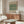 May include: Framed vintage botanical poster featuring William Morris's green Tulip pattern from 1875 displayed above a mid-century modern walnut credenza. Room scene shows cream upholstered chair, glass oval coffee table, brass floor lamp, and minimalist decor in neutral tones with natural lighting.