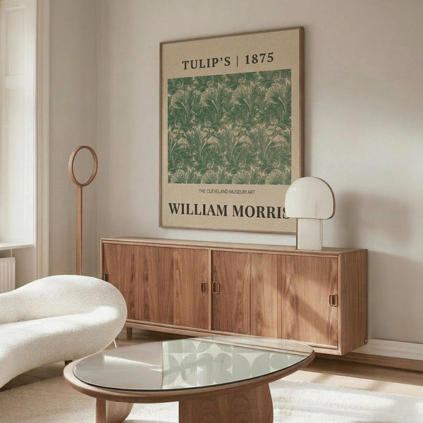 May include: Framed vintage botanical poster featuring William Morris's green Tulip pattern from 1875 displayed above a mid-century modern walnut credenza. Room scene shows cream upholstered chair, glass oval coffee table, brass floor lamp, and minimalist decor in neutral tones with natural lighting.