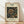 May include: Framed poster with William Morris honeysuckle pattern from 1876 displayed against white wall on wooden floor. Features intricate floral design with large stylized honeysuckle blooms and twisting vines in gold and green tones on dark blue background. Light wooden frame with cream matting. Natural sunlight creates soft shadows across the scene.