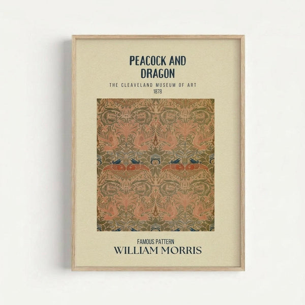 May include: Framed poster print displaying William Morris's ornate Peacock and Dragon pattern from 1878. Features intricate botanical design with stylized peacocks, dragons, and foliage in muted coral, olive green, and blue tones. Text identifies it as from The Cleveland Museum of Art collection. Light wood frame against cream matting, mounted on white wall with subtle shadow.