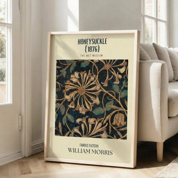 May include: Framed vintage botanical poster featuring William Morris's ornate honeysuckle pattern from 1876 in deep teal and golden tones, leaning against white wall beside beige upholstered sofa in bright living room with large windows and natural lighting.
