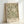 May include: Framed botanical art print featuring William Morris-style flowing foliage pattern in sage green and cream tones on beige background, displayed in light wood frame leaning against white wall corner with soft natural lighting