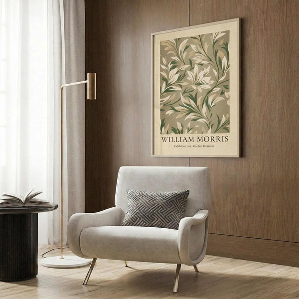 May include: Framed botanical poster with green and cream leaf pattern hanging on wood paneled wall above beige upholstered armchair with geometric patterned pillow, brass floor lamp, and dark round side table with open book in modern neutral-toned room setting