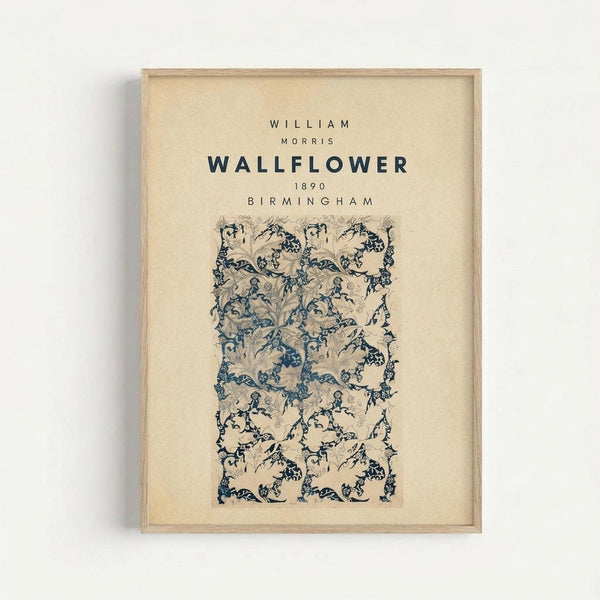 May include: Framed vintage botanical wallpaper design print in light wood frame hanging on white wall. Features intricate blue and beige floral pattern with flowing vines, leaves, and ornate Victorian-style motifs. Typography at top displays designer name, pattern name, year 1890, and location Birmingham in dark blue text on cream background.