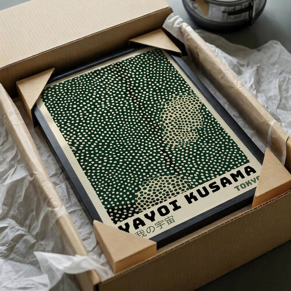 A framed poster with a green and white dotted pattern, sitting in a cardboard box.