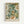 A framed botanical art print featuring an intricate floral pattern with cream and white flowers, sage green foliage, and orange accents in William Morris's distinctive Arts and Crafts style. The artwork displays flowing, organic forms with detailed leaves and blooms against a darker background. Below the illustration, text reads "WILLIAM MORRIS Exhibition Art - Floral Fantasy" on a cream-colored border. The print is displayed in a light wooden frame against a white wall.