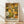 May include: Framed art print featuring colorful floral dot pattern in yellows, oranges, greens, and whites on cream background, displayed against white textured wall on light wood floor. Print shows dense arrangement of stylized flowers and polka dots in warm autumn tones with "YAYOI KUSAMA" and Japanese text at bottom. Natural wood frame with light finish complements the organic botanical design.