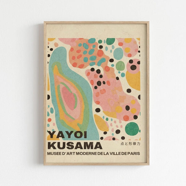 May include: Framed abstract art print with organic flowing shapes in turquoise, coral pink, yellow, and green, scattered with black dots of various sizes. The wavy forms create layered, concentric patterns reminiscent of geological formations. Text at bottom reads "YAYOI KUSAMA" and "MUSEE D'ART MODERNE DE LA VILLE DE PARIS" with Japanese characters. Light wood frame against white wall.
