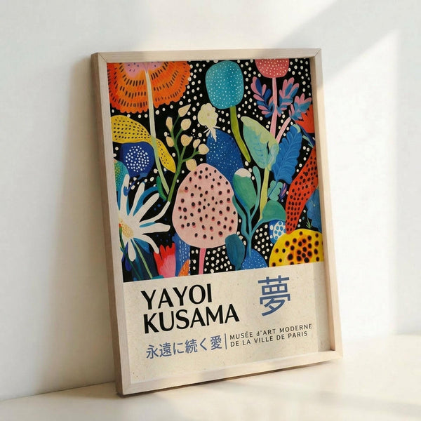 May include: Framed poster print featuring colorful abstract botanical artwork with vibrant flowers, leaves, and organic shapes in orange, blue, pink, yellow, and green against black dotted background. Text shows "Yayoi Kusama" and Japanese characters below the artwork. Light wooden frame leans against white wall on light surface.