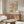 May include: Colorful abstract art poster with pink, teal, yellow, and black dots and organic shapes in thin wood frame, displayed above walnut sideboard in minimalist living room with white curved chair, glass coffee table, and white table lamp