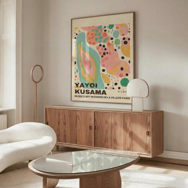 May include: Colorful abstract art poster with pink, teal, yellow, and black dots and organic shapes in thin wood frame, displayed above walnut sideboard in minimalist living room with white curved chair, glass coffee table, and white table lamp
