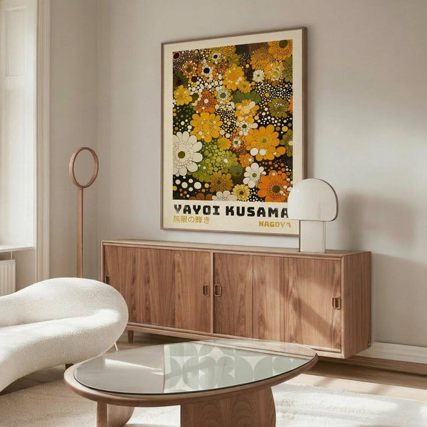 May include: Framed poster featuring colorful floral pattern with yellow, orange, green and white blooms and polka dots on dark background, displayed above wooden sideboard in modern living room with white curved chair, glass coffee table, and table lamp