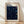 May include: Framed poster with cream matting and light wood frame leaning against white wall on wooden floor. Features dark blue cosmic design with swirling patterns, scattered circular dots in blue, yellow and white representing stars and planets. Text reads "YAYOI KUSAMA" at top with Japanese characters and "1991 MUSEUM OF MODERN ART NEW YORK EXHIBITION ART" at bottom.