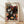 May include: Framed art poster featuring Yayoi Kusama's iconic polka dot mushroom artwork on black background with colorful spotted fungi in pink, orange, blue, and white patterns. Wooden frame displays against white wall with natural lighting casting shadows. Museum exhibition poster from 1972 with bold black text header and Japanese characters.