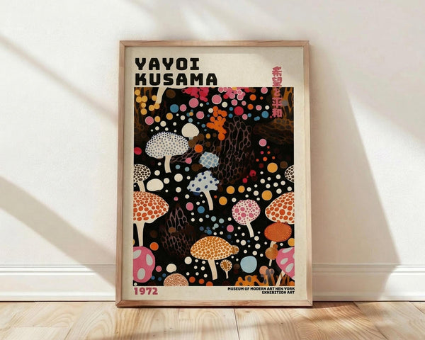May include: Framed art poster featuring Yayoi Kusama's iconic polka dot mushroom artwork on black background with colorful spotted fungi in pink, orange, blue, and white patterns. Wooden frame displays against white wall with natural lighting casting shadows. Museum exhibition poster from 1972 with bold black text header and Japanese characters.