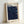 May include: Framed art print leaning against white wall showing dark navy blue swirling pattern with colorful polka dots in blues, yellows, and greens scattered throughout. Text reads "YAYOI KUSAMA" at top with Japanese characters and "1991" at bottom. Light wood frame with white matting, Museum of Modern Art attribution visible.