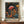 May include: Framed art print featuring vibrant mushrooms in Kusama's distinctive polka dot style against a dark starry background, displayed on a wooden sideboard next to a white ceramic vase and stacked books. The artwork shows colorful spotted mushrooms in reds, oranges, and blues with Japanese text below. The print has a brown wooden frame and creates a whimsical, psychedelic botanical scene with scattered dots throughout the composition.