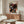 May include: Colorful Yayoi Kusama exhibition poster featuring whimsical mushrooms and polka dots on black background, displayed above mid-century modern walnut credenza in minimalist living room with cream chair, glass coffee table, and neutral walls