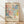 May include: Framed poster with colorful dotted abstract pattern in pink, blue, yellow and coral tones, featuring "YAYOI KUSAMA" text and Japanese characters below the artwork. Light wood frame leaning against white wall on wooden floor with soft natural lighting and shadows.