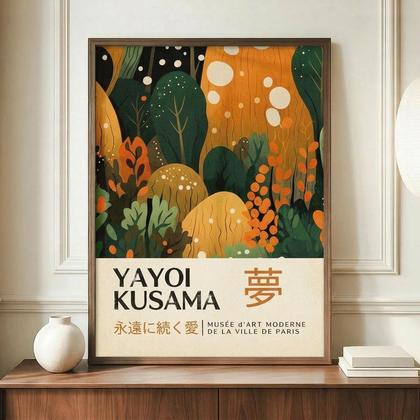 May include: Framed art poster featuring abstract botanical illustration with green foliage, orange and yellow organic shapes, white dots, and Japanese text reading "Yayoi Kusama" with "Musée d'Art Moderne de la Ville de Paris" below. Displayed on wooden sideboard next to white ceramic vase and books in modern room with white walls and paneled wainscoting.