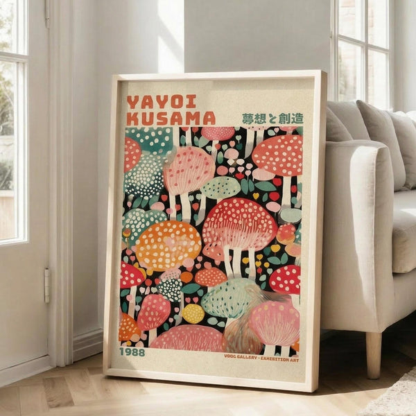 May include: Colorful framed poster featuring vibrant mushrooms and polka dot patterns in red, orange, pink, green, and yellow tones against black background. Japanese text at top. Light wood frame leaning against white wall next to beige upholstered chair in bright living room with large windows.