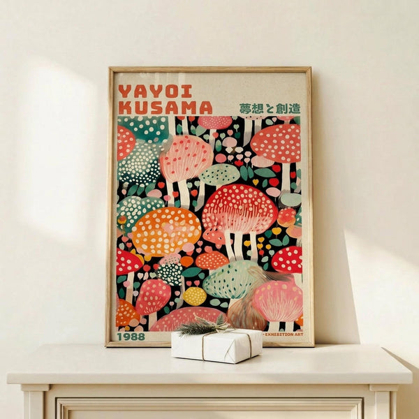 May include: A framed poster featuring colorful illustrated mushrooms in various sizes and patterns, displayed on a light wood console table with a small wrapped gift beside it. The artwork shows vibrant red, orange, pink, green, and yellow mushrooms with polka dots and organic shapes against a dark background, presented in a simple wooden frame against a cream wall.