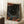 May include: Framed poster with abstract cosmic design featuring swirling flowing lines, colorful dots and circles in orange, red, blue tones against dark background, displayed leaning against white wall corner next to wooden side table with coffee cup, on textured cream rug beside beige furniture in bright natural lighting